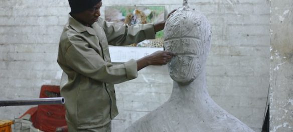 man sculting clay face of a statue